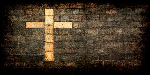 grungy cross of christ built into a brick wall as background